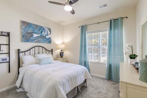 A bedroom with a bed, nightstand, and a painting on the wall.