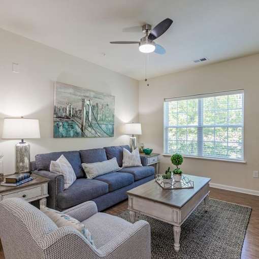 A living room with a grey couch, a coffee table, and a painting on the wall.