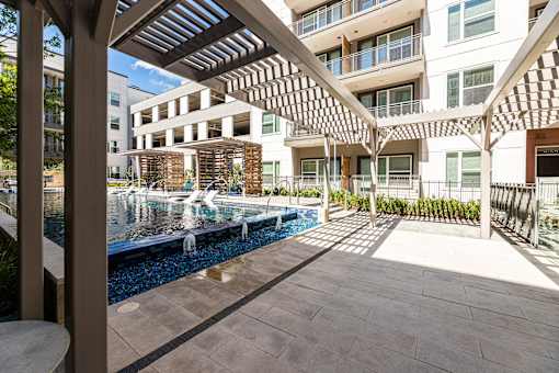 A modern building with a pool and a wooden pergola.