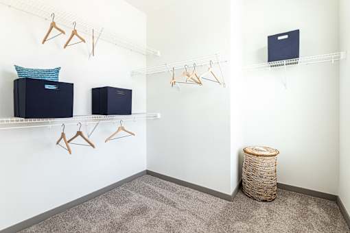 A room with a white wall and a shelf with clothes hangers and a laptop on it.