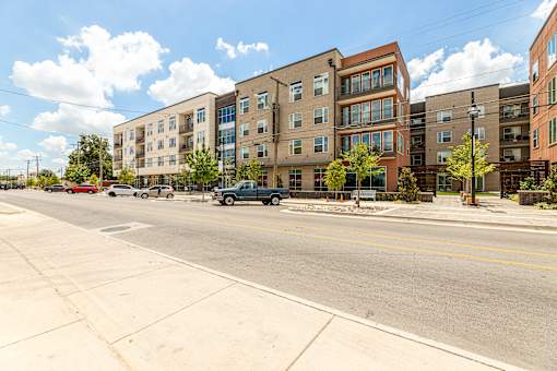 A street view of a residential area with cars parked on the side of the road.