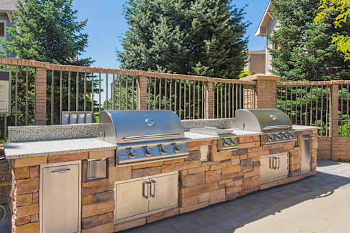 A stone and wood outdoor kitchen with a grill and sink.