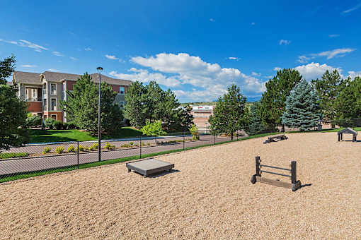 A sandy playground area with a slide and a bench.