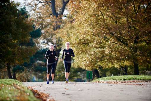two women running down a path in a park