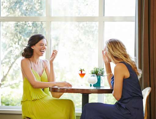two women sitting at a table laughing and talking