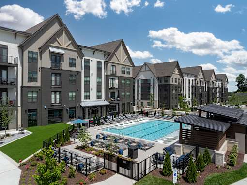 A large apartment complex with a pool and a gated fence.