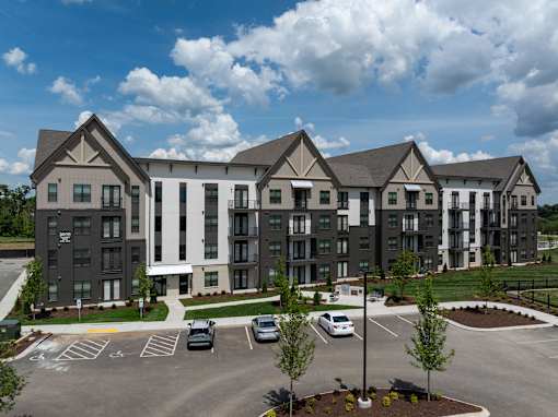 A large, modern apartment complex with a parking lot in front.