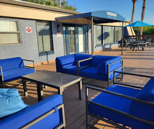A patio with blue cushioned chairs and a table.