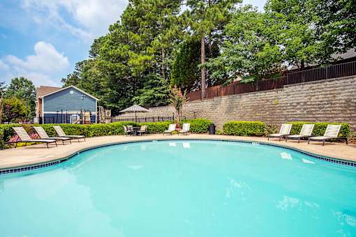 A swimming pool surrounded by trees and a building.