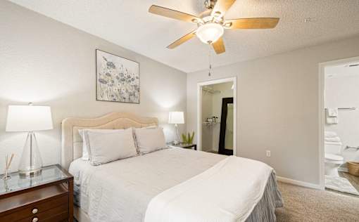A bedroom with a bed, nightstand, and a ceiling fan.