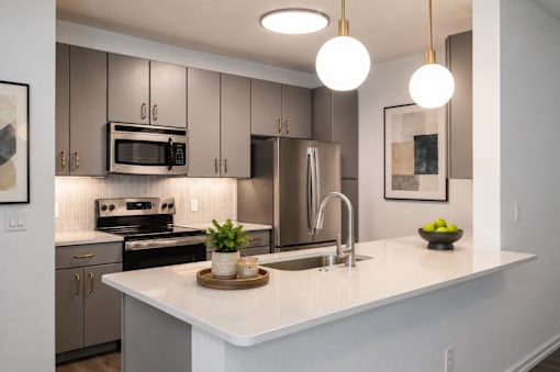 A modern kitchen with a white countertop and stainless steel appliances.