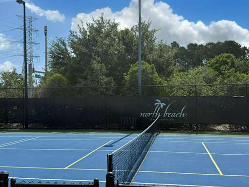 A tennis court with a black fence and the words "North Beach" written on it.