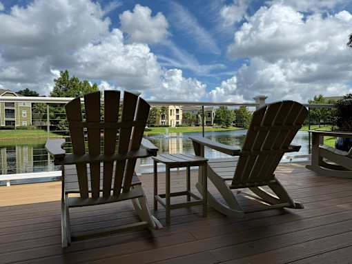 Two chairs and a table are on a wooden deck.