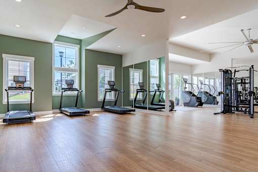 A spacious gym with treadmills, elliptical machines, and a weight rack.