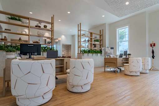 A modern office space with white furniture and wooden shelves.