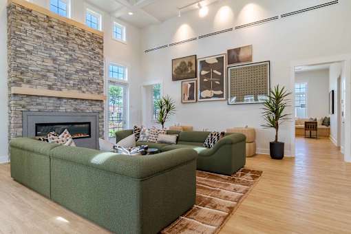 A living room with a stone fireplace and green couches.