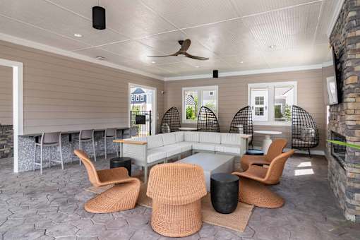A modern outdoor living space with a white ceiling fan and a stone wall.