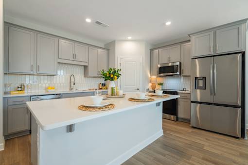 A modern kitchen with a white island and stainless steel appliances.