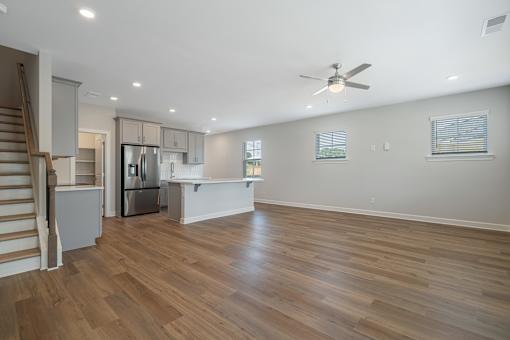 A spacious kitchen with wooden floors and a ceiling fan.