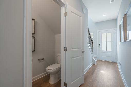 A white toilet in a small bathroom with a door open to a hallway.