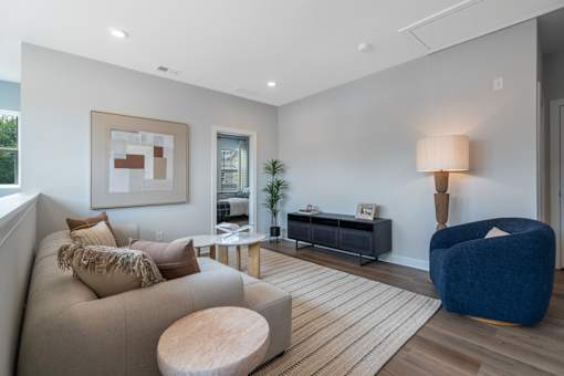A living room with a beige couch, a blue chair, and a wooden coffee table.