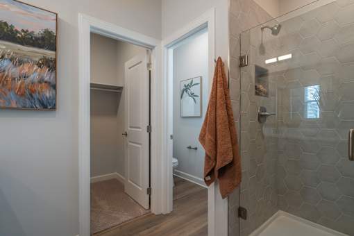 A bathroom with a towel hanging on the shower door.