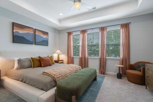 A bedroom with a bed, a chair, and two pictures on the wall.