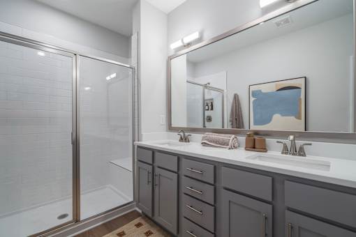 A bathroom with a white sink, a mirror, and a shower with a glass door.