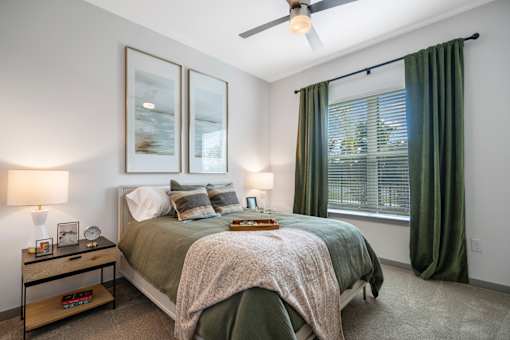 A bedroom with a bed, nightstand, and window.