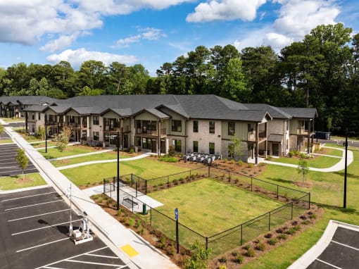 an aerial view of an apartment complex with a tennis court and lawn