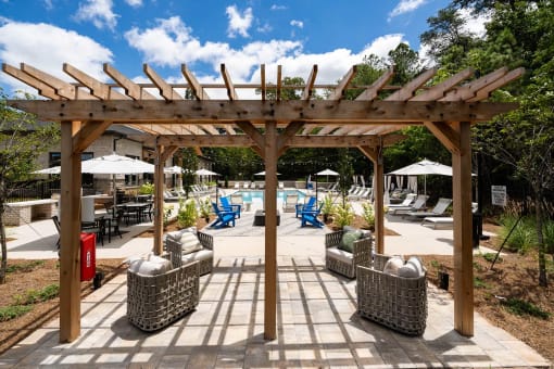 a patio with a pergola and chairs around a pool