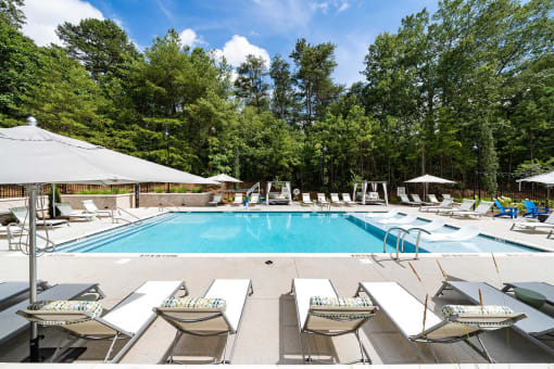 a swimming pool with lounge chairs and umbrellas