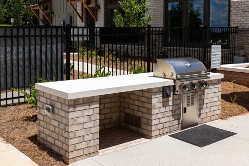 a brick outdoor grill area in front of a fence