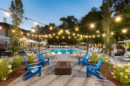 a patio with chairs and a pool at night