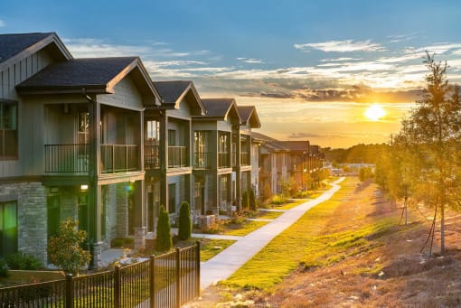 One-Bedroom Apartments in Acworth, GA - The Brookstone - Exterior View of Apartment Homes with Concrete Walking Path, Manicured Grass, and Trees.