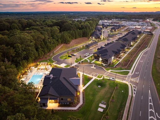 an aerial view of a resort with a swimming pool at dusk