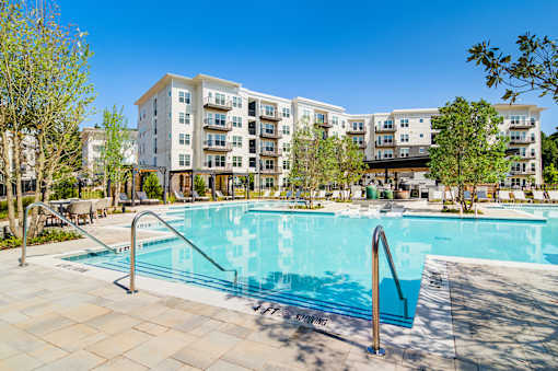 A large swimming pool in front of apartment buildings.