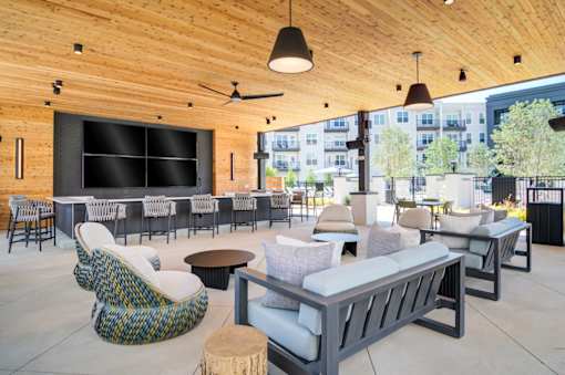 A modern outdoor seating area with wooden ceiling and furniture.