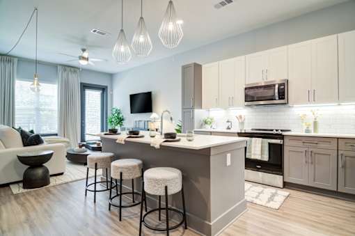 A modern kitchen with a bar area and a living room area.