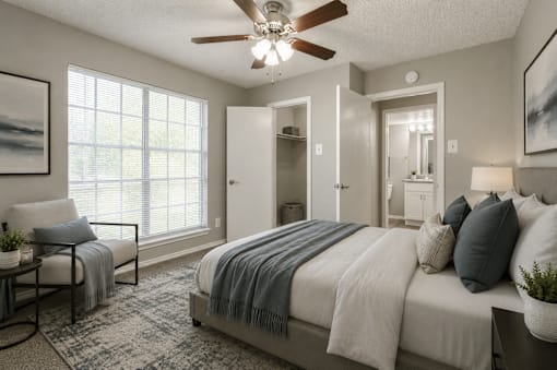 A bedroom with a bed, chair, and a ceiling fan.