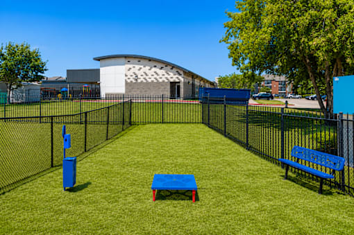 A park with a blue bench and a blue trash can.