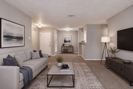 A living room with a grey couch, a coffee table, and a painting on the wall.