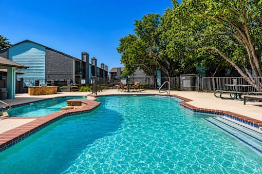A swimming pool with a blue tiled edge and a red brick border.