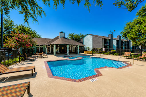 A pool surrounded by a black fence and a building in the background.
