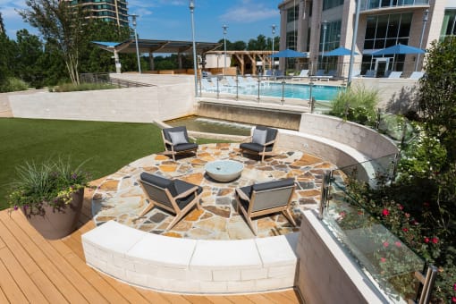 a patio with a fire pit and a pool in the background