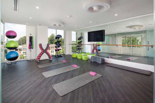 a yoga studio with yoga mats on the floor and a tv on the wall