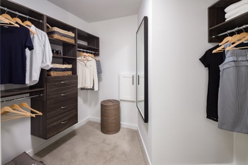 a walk in closet in a home with white walls and a gray carpet