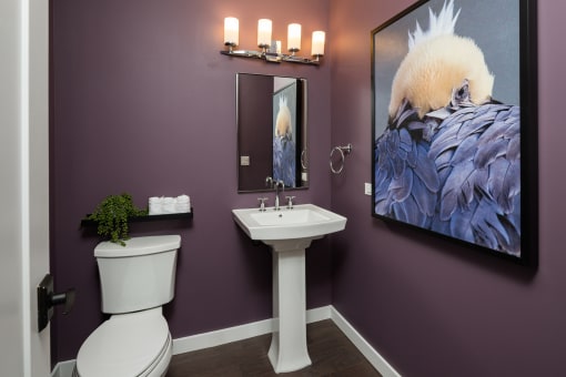 a bathroom with purple walls and a large painting on the wall