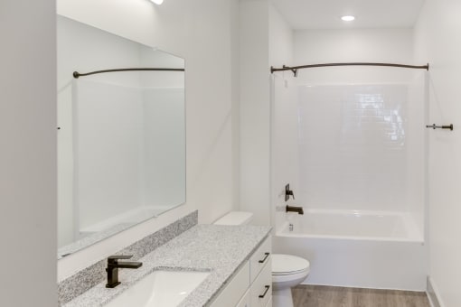 a bathroom with white walls and a white toilet next to a white sink with a large mirror