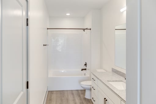 a bathroom with white walls and a white toilet next to a white bathtub